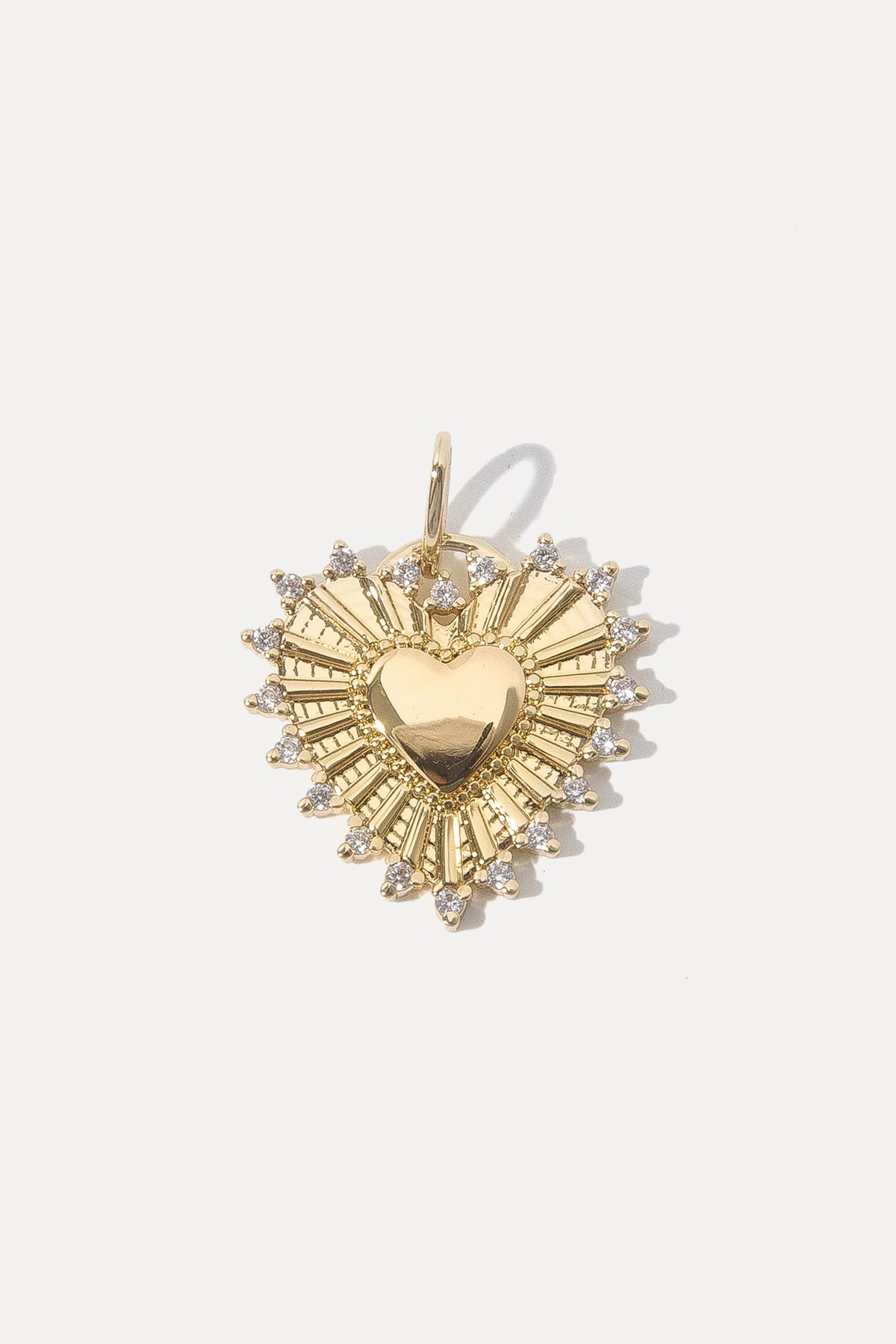 Gold heart-shaped Adorn Charm with sunburst rays and CZ border flat lay on a white background.