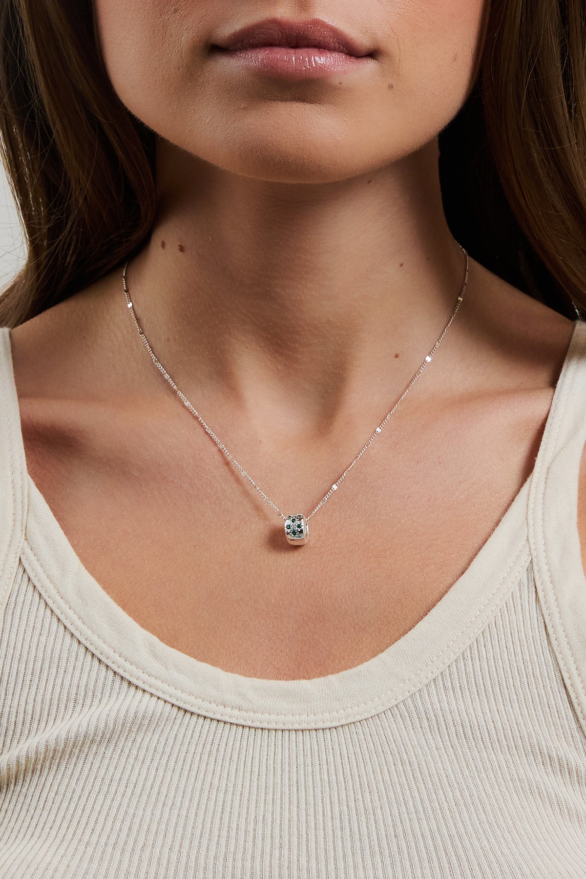 Model wearing silver Celeste Slider charm on a delicate coco chain, styled with a cream ribbed tank.