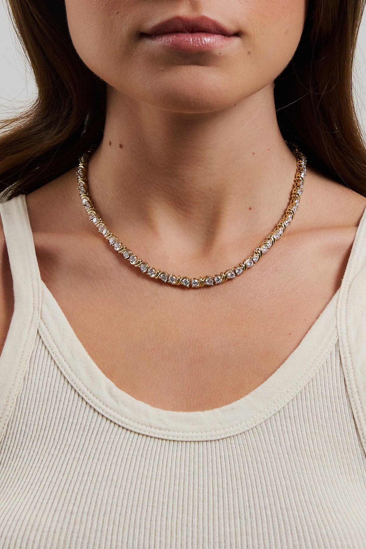 Model wearing gold Delilah tennis necklace with CZ stones, styled with a low-cut cream ribbed tank.