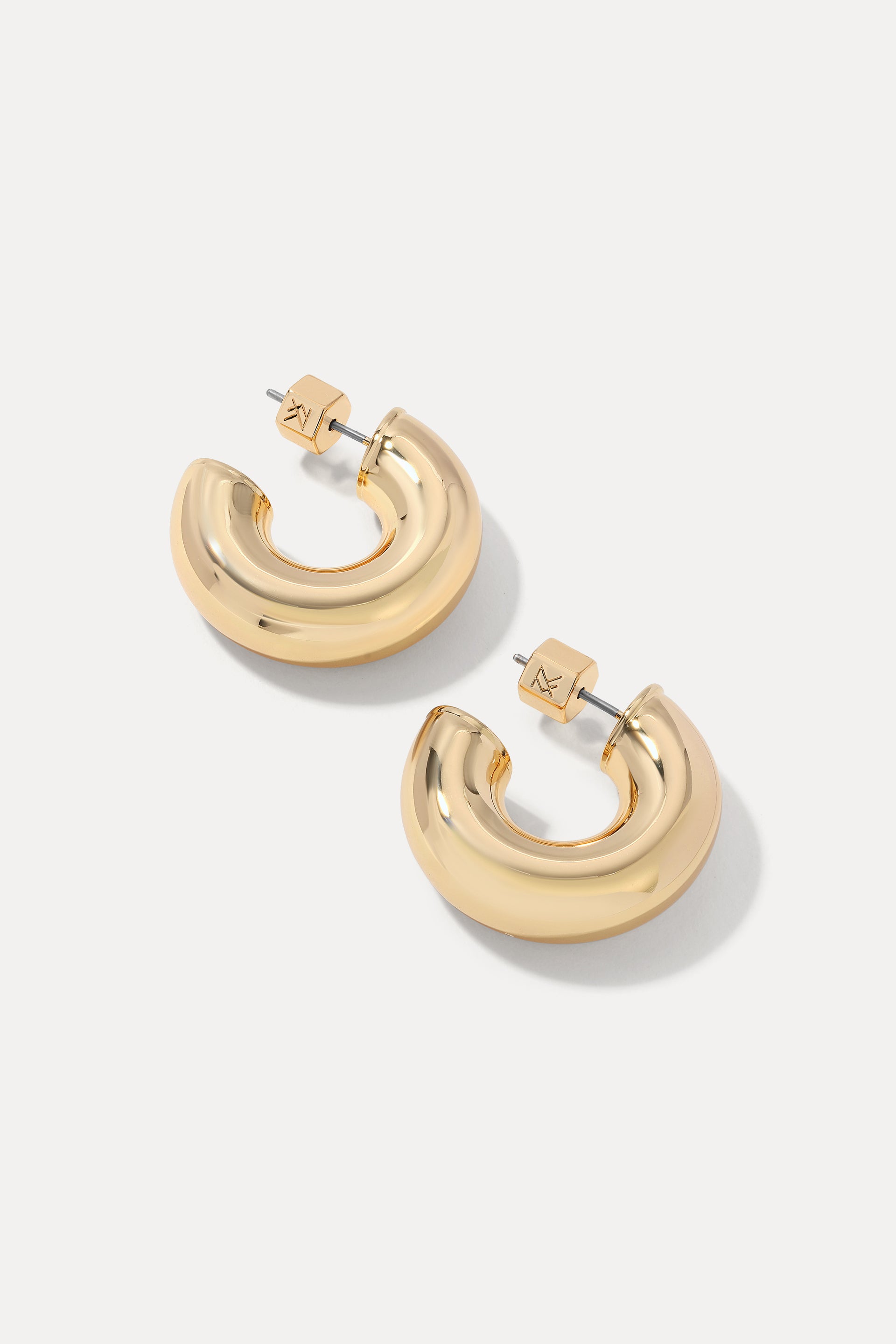 Gold thick rounded Drew huggie hoop earrings displayed on a plain white background.