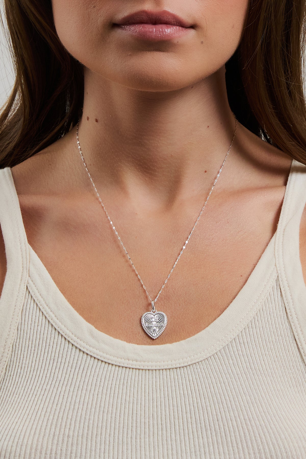 Model wearing silver Forever Charm on a nora chain, styled with a cream ribbed tank.