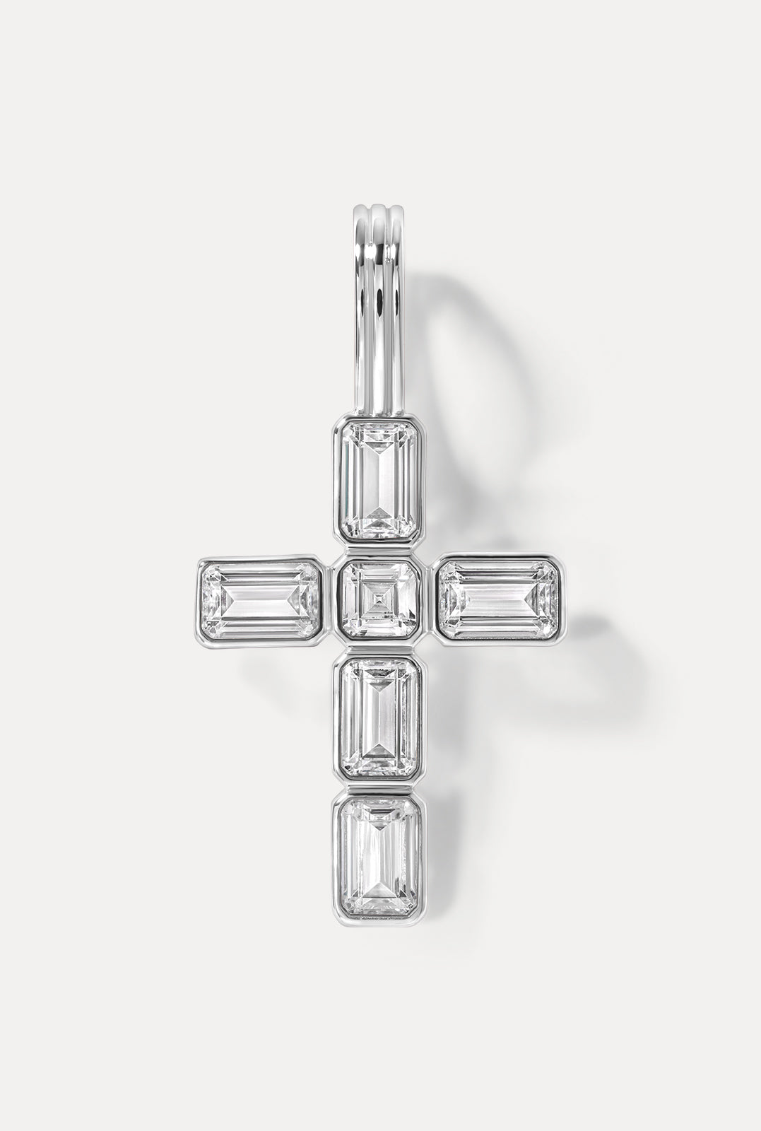 Diamond cross pendant in silver showcasing it's emerald cut CZ's on a white background.