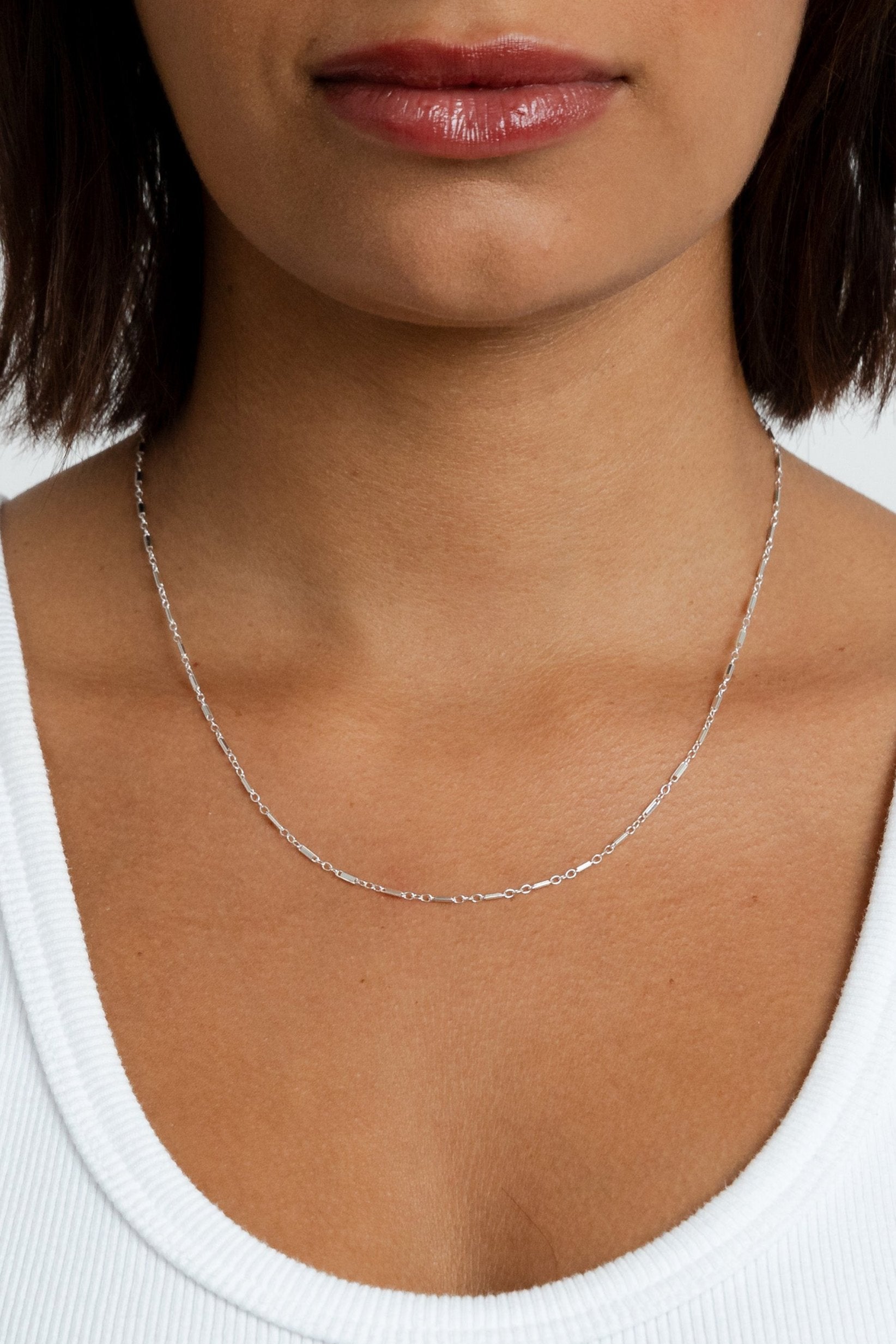 Model showcasing the silver Lindsey Chain necklace resting lower on her neckline.