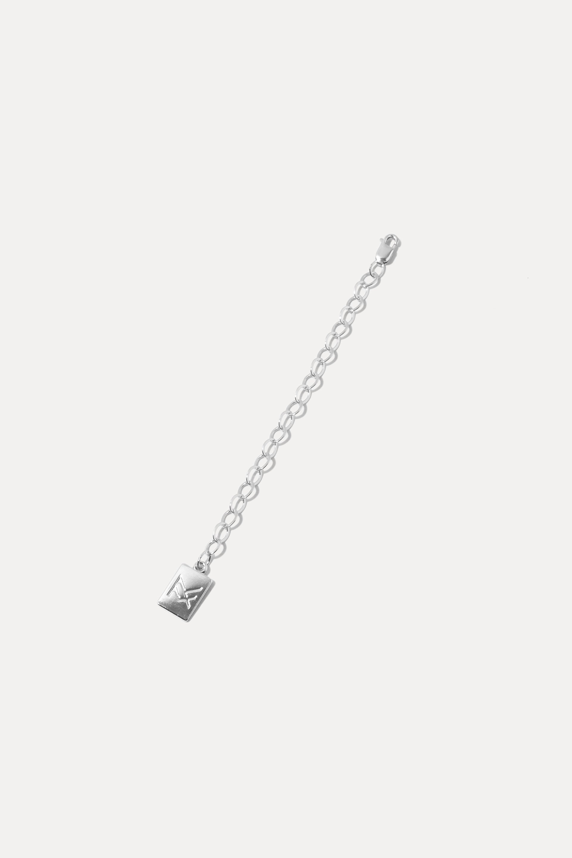 Sterling silver necklace extender chain with logo charm tag, displayed on a clean white background.