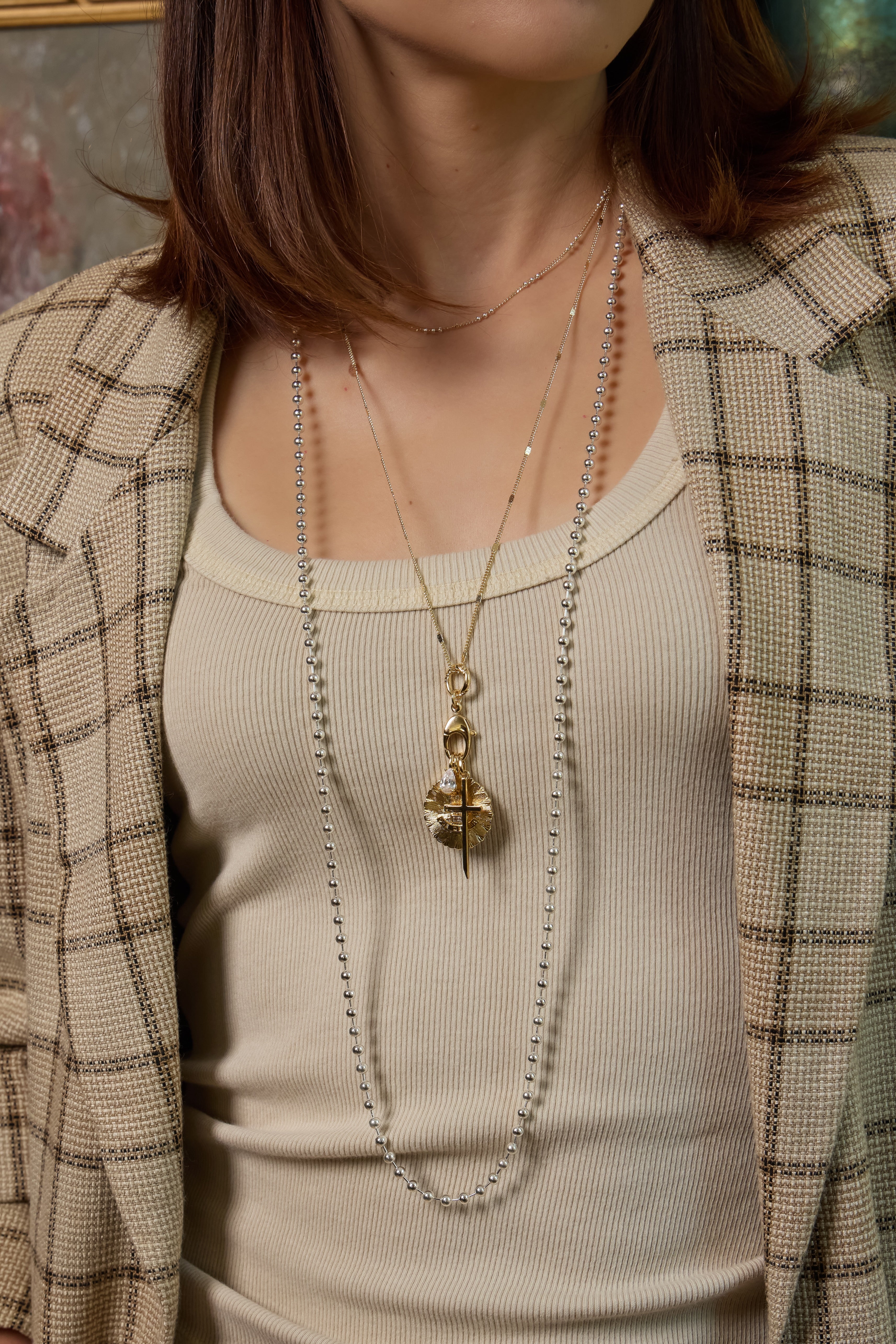 Model wearing the Sutton charm on a gold Coco chain and Amelia necklace in silver.