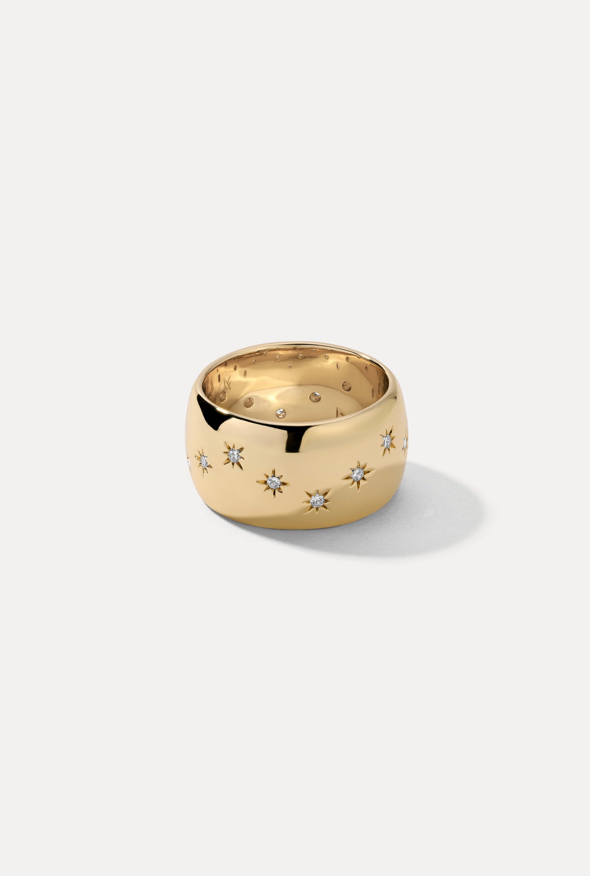 Gold Celeste wide cigar band ring featuring engraved starburst settings with CZ stones on a white backdrop.