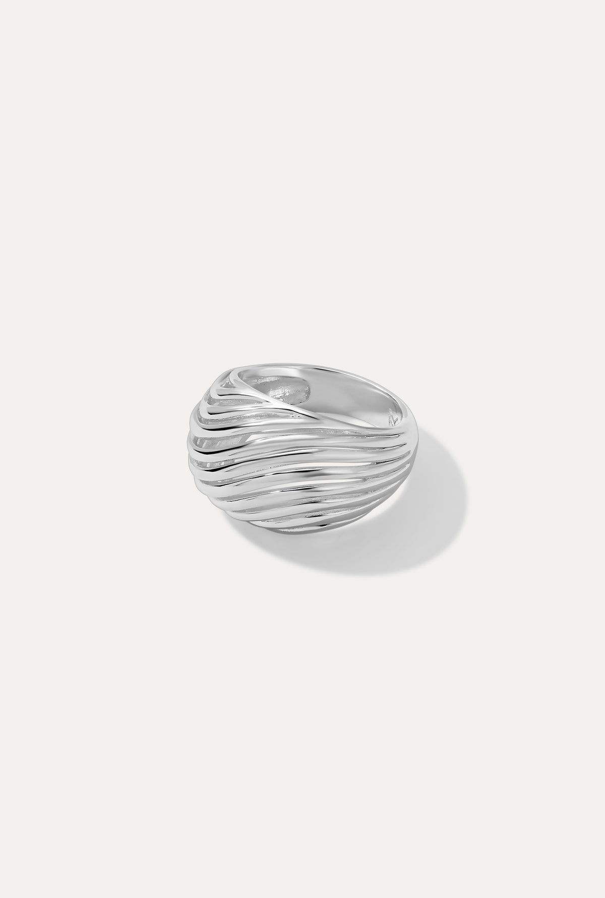 Silver Etta dome ring featuring a wide band with a sculpted, openwork wavy design on a white backdrop.