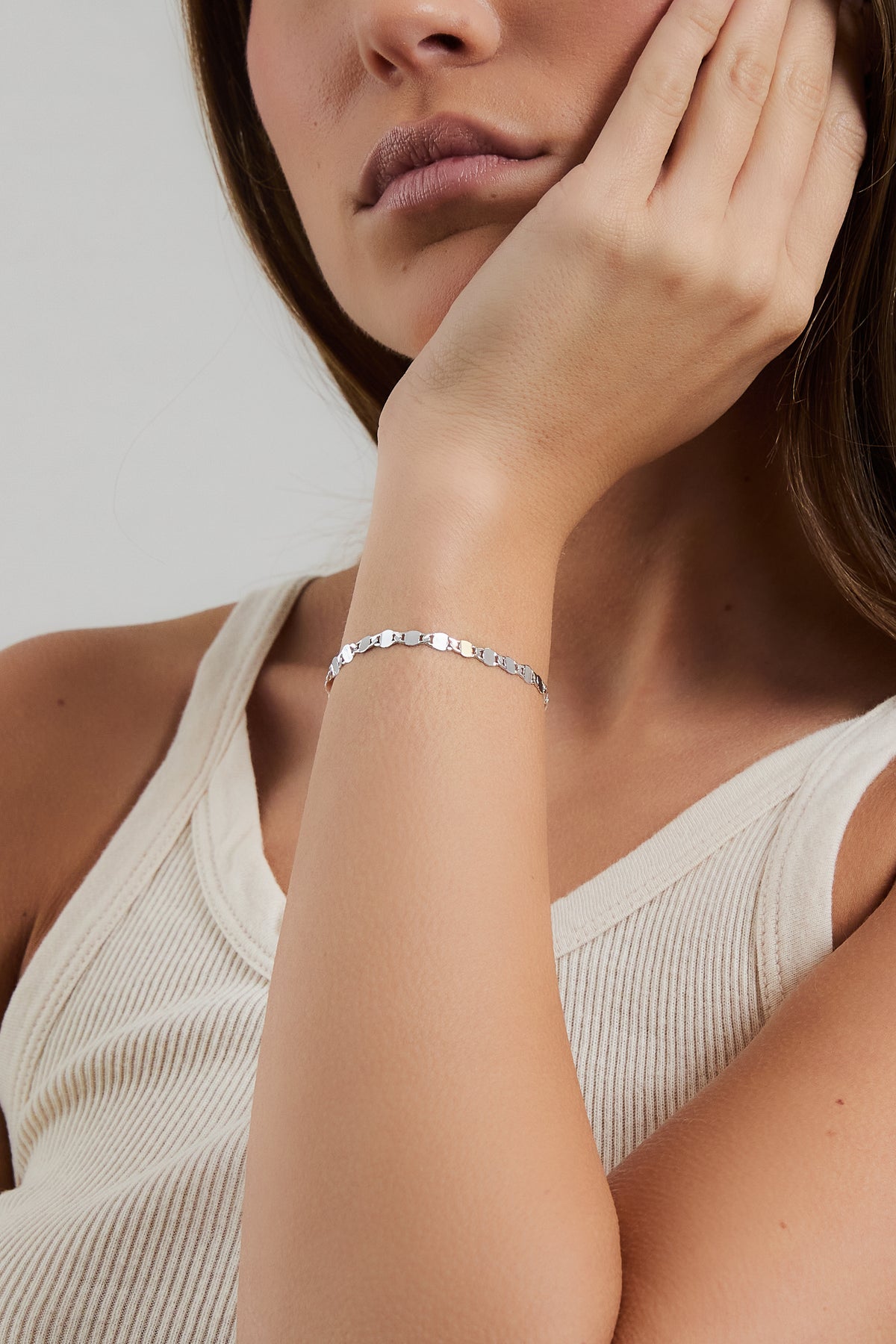 Model wearing silver Ava mirror chain bracelet, styled with a cream ribbed tank.