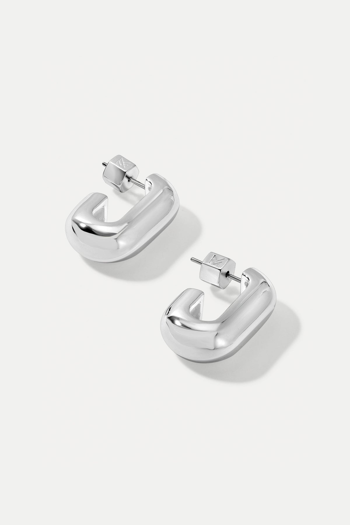 Silver Ellie huggie hoop earrings with smooth contoured edges on a plain white background.