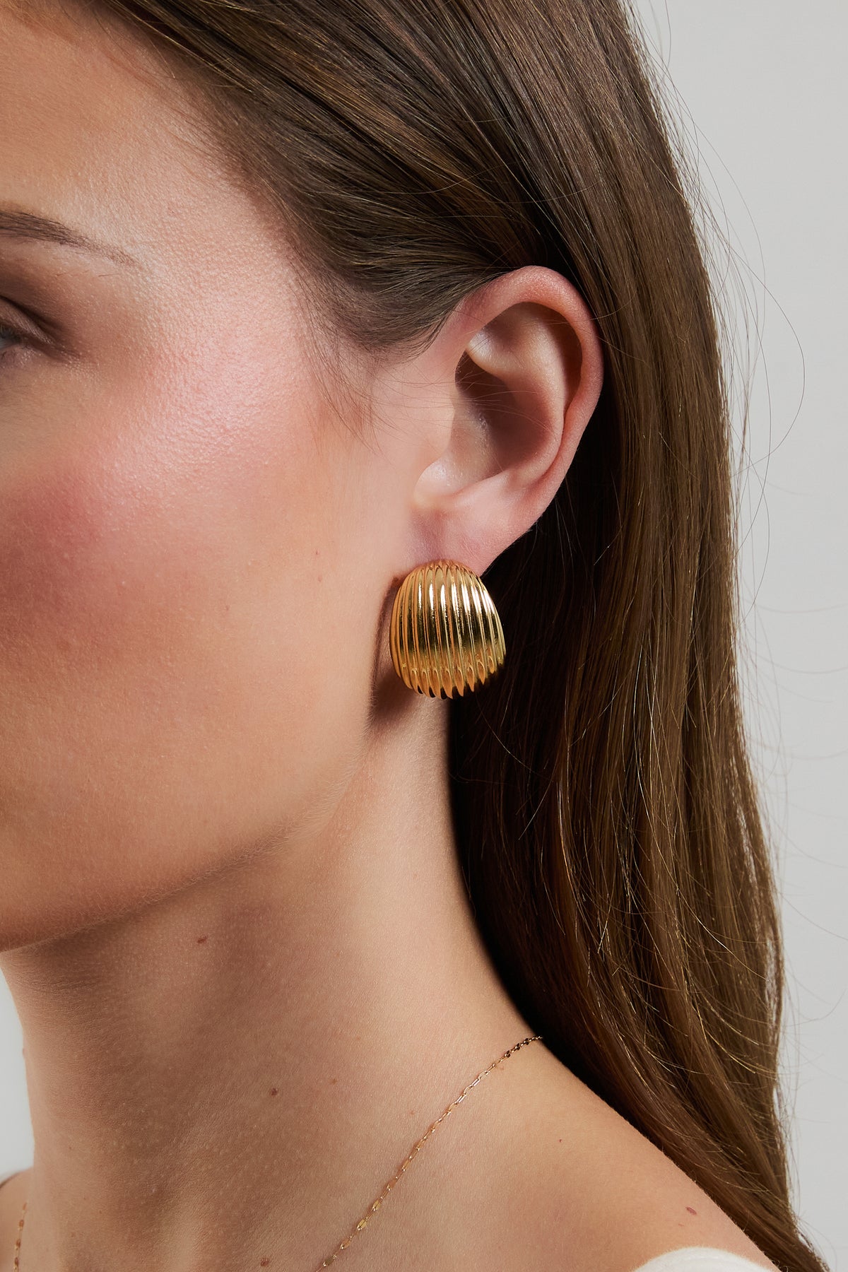 Model wearing gold Florence ribbed dome hoop earring.