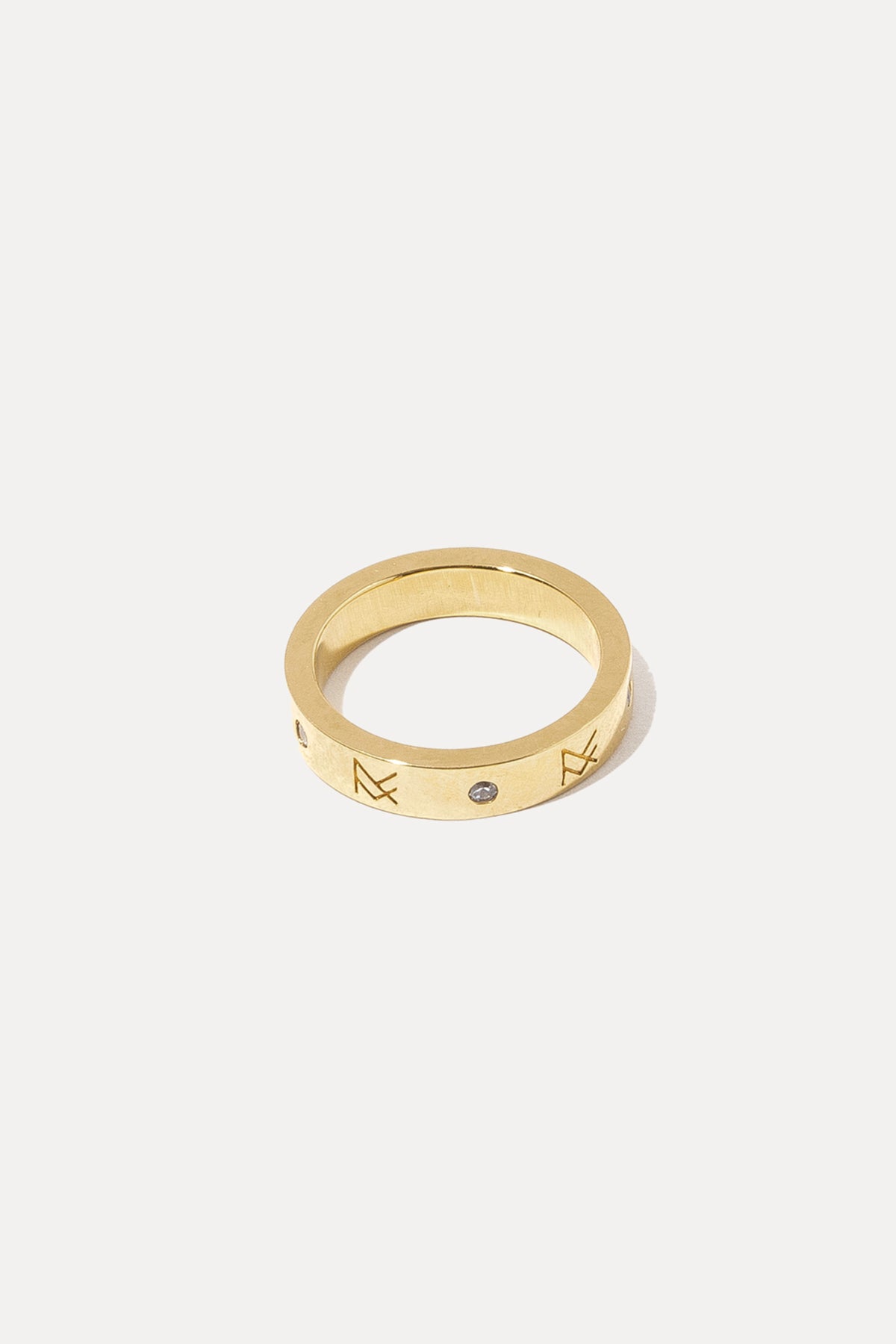 Gold MF ring featuring a detailed crest design, centered on a plain white background.
