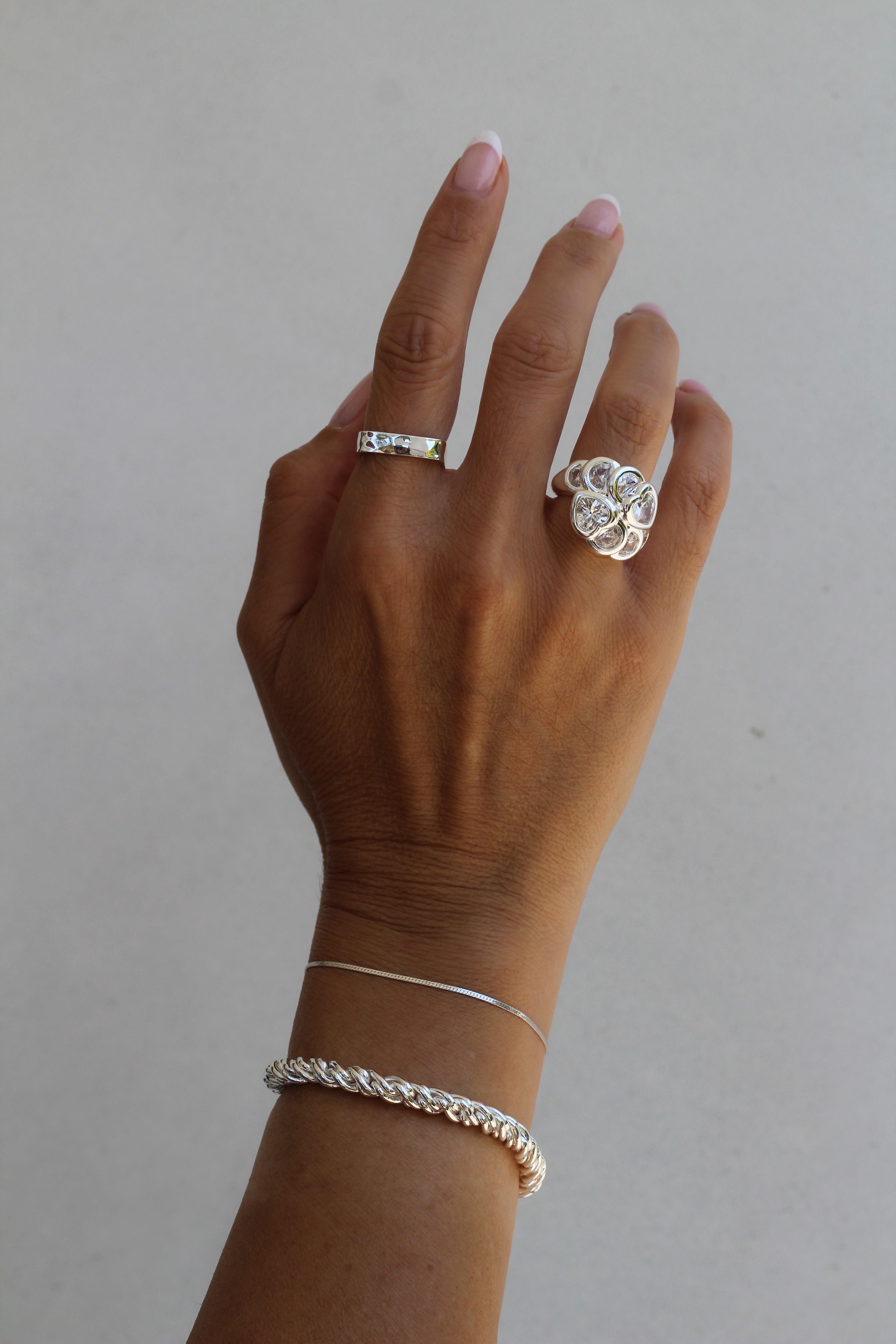 Close-up of a model's wrist wearing the sterling silver Josephine and Adriana bracelets paired with the Bardot and Mae ring.