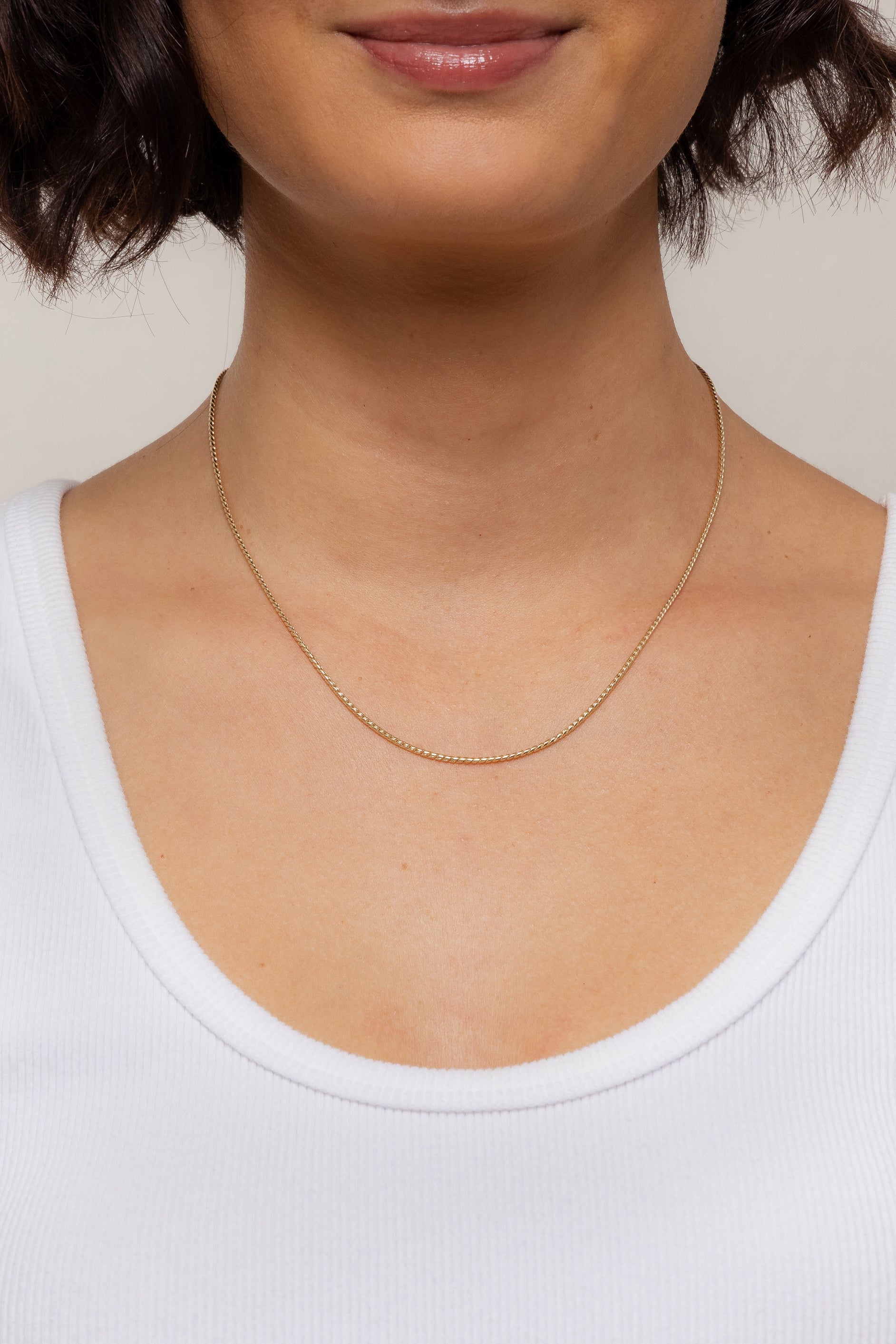 Model showcasing the gold filled Mina Chain necklace resting lower on her neckline.