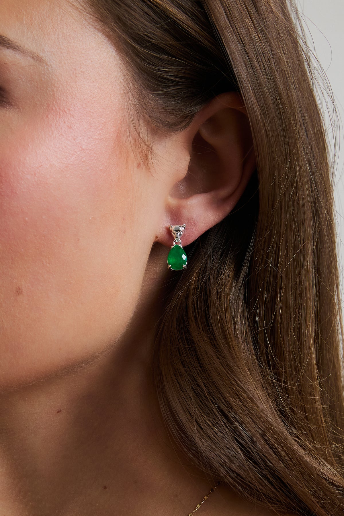 Model wearing silver Panther Emerald drop earring with green teardrop gem, featuring sculpted panther stud.