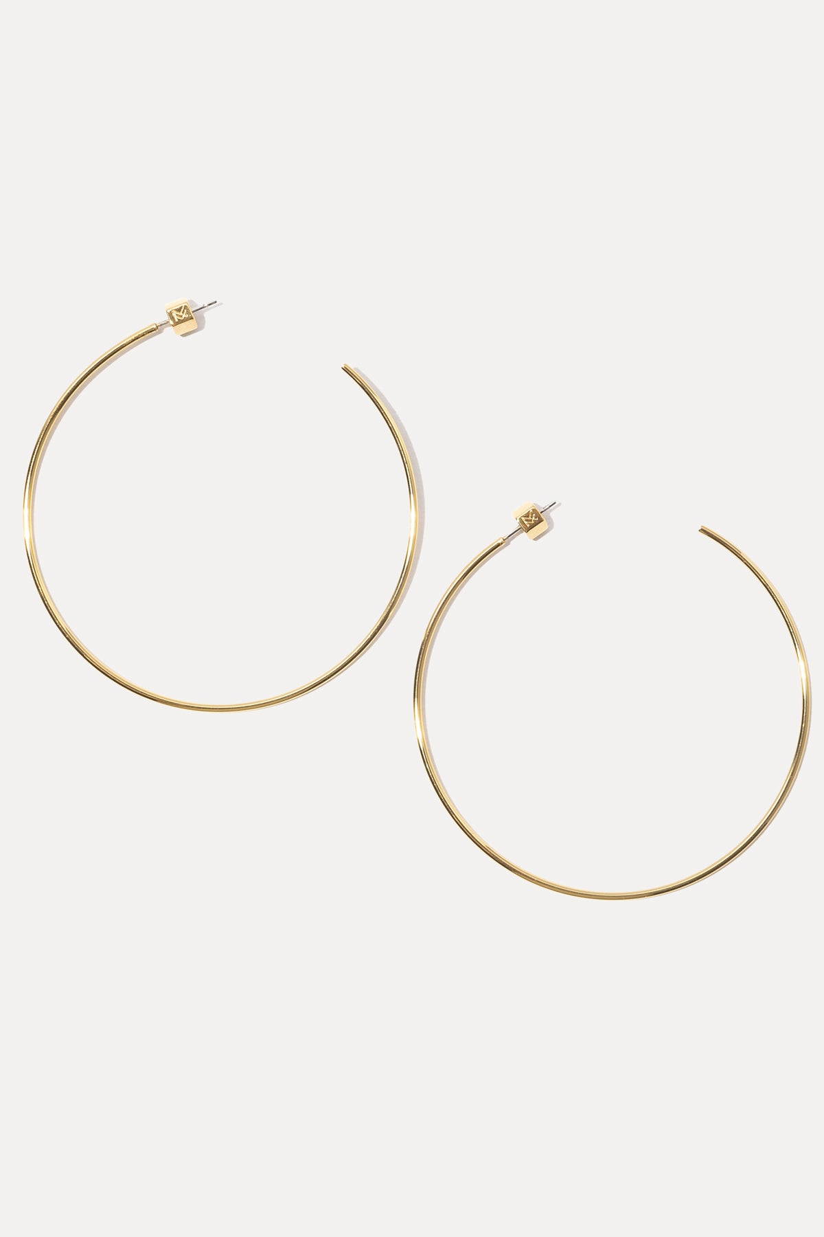 Pair of gold Rylan Hoops on a white background showing custom MF earring backings.