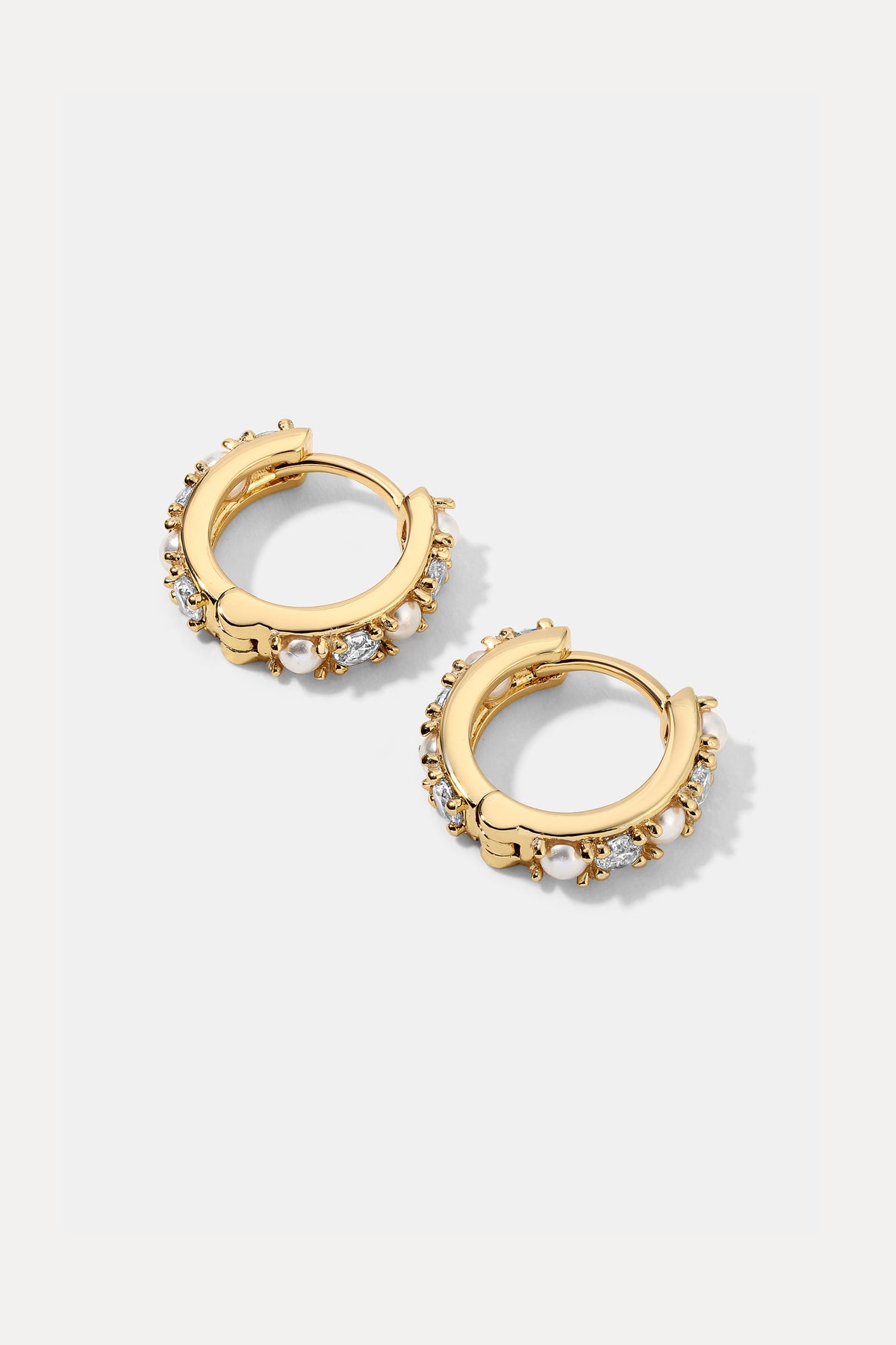 Pair of gold Wendy Huggies featuring pearls and cubic zirconia stones on a white background.
